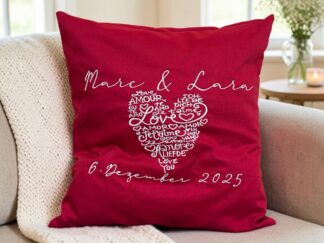 Hochzeitskissen rot liegend auf einem gemütlichen Sofa, bestickt mit Namen und Datum sowie einem grossen Herz
