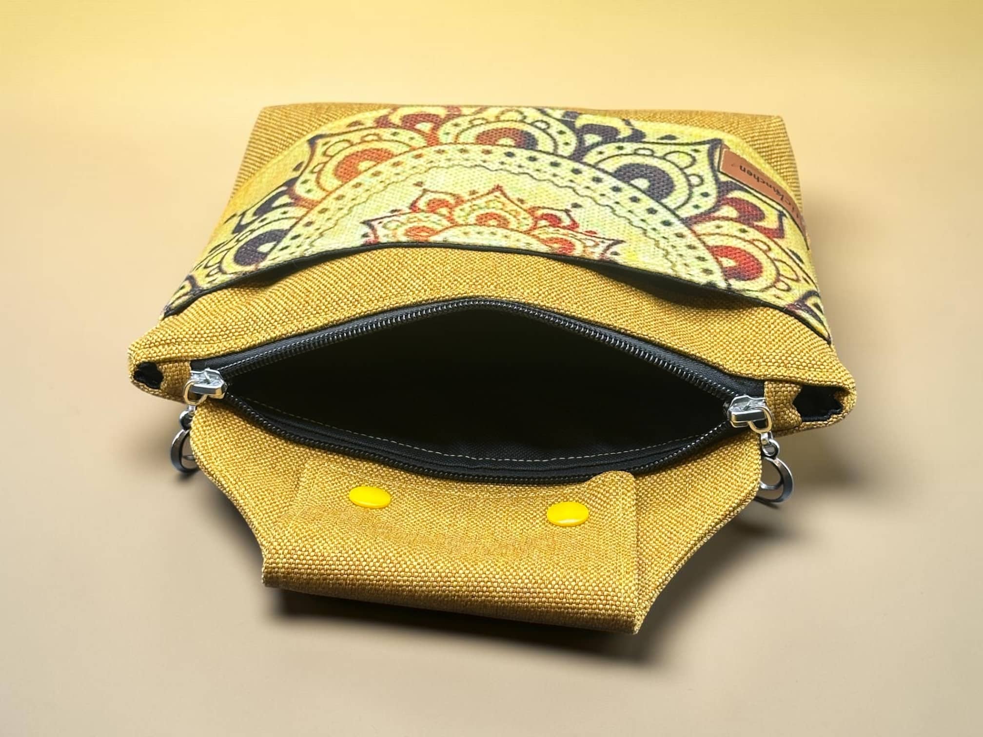 Yellow textured backpack with a colorful patterned flap, zippers open to reveal the dark interior.