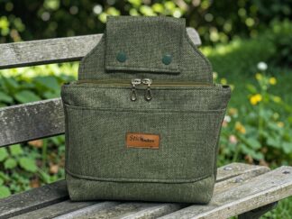 Olive-green textured backpack resting on a weathered wooden bench outdoors with greenery in the background.